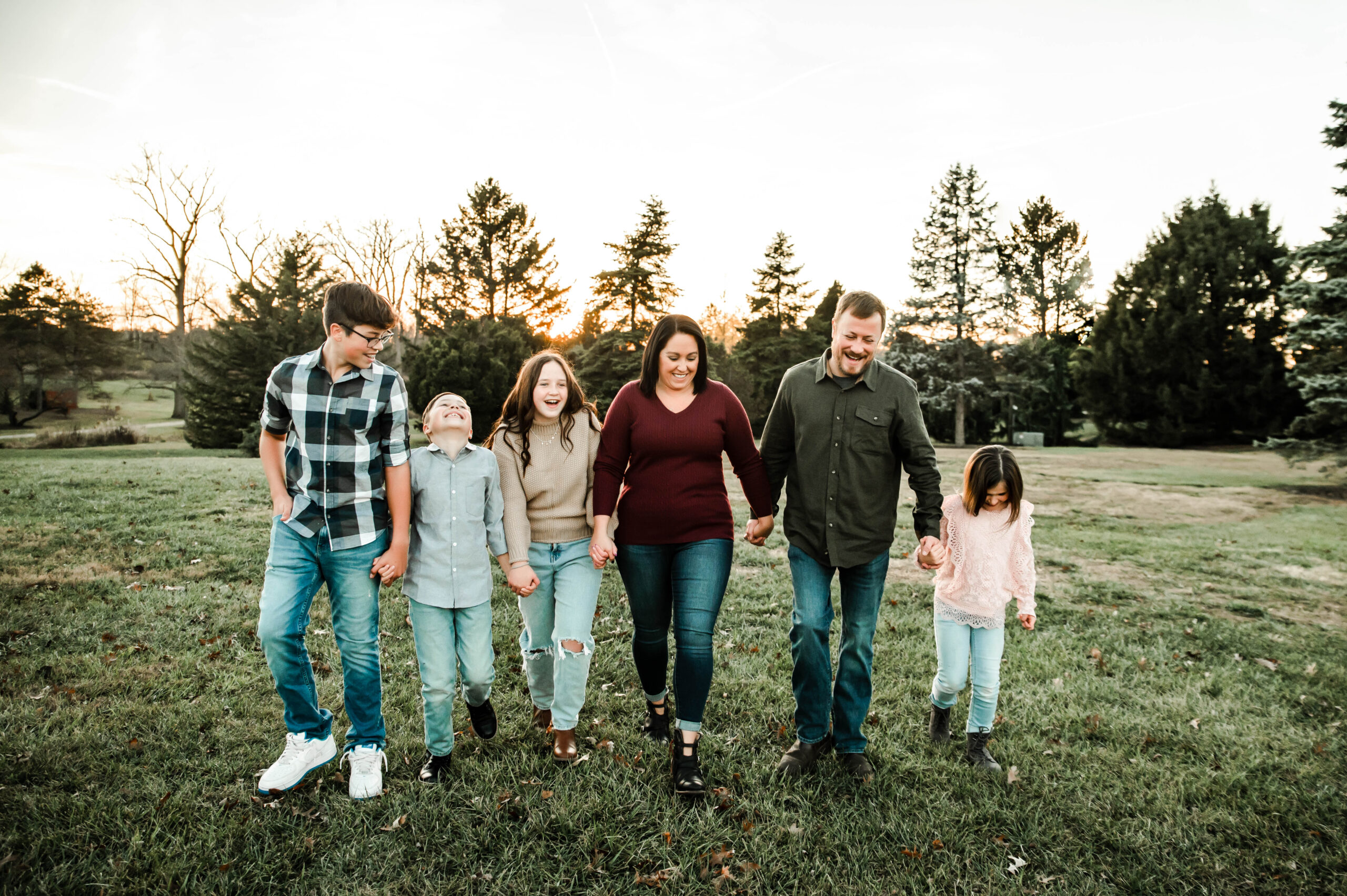 Family walking through park laughing and holding hands. Family photos in cincinnati