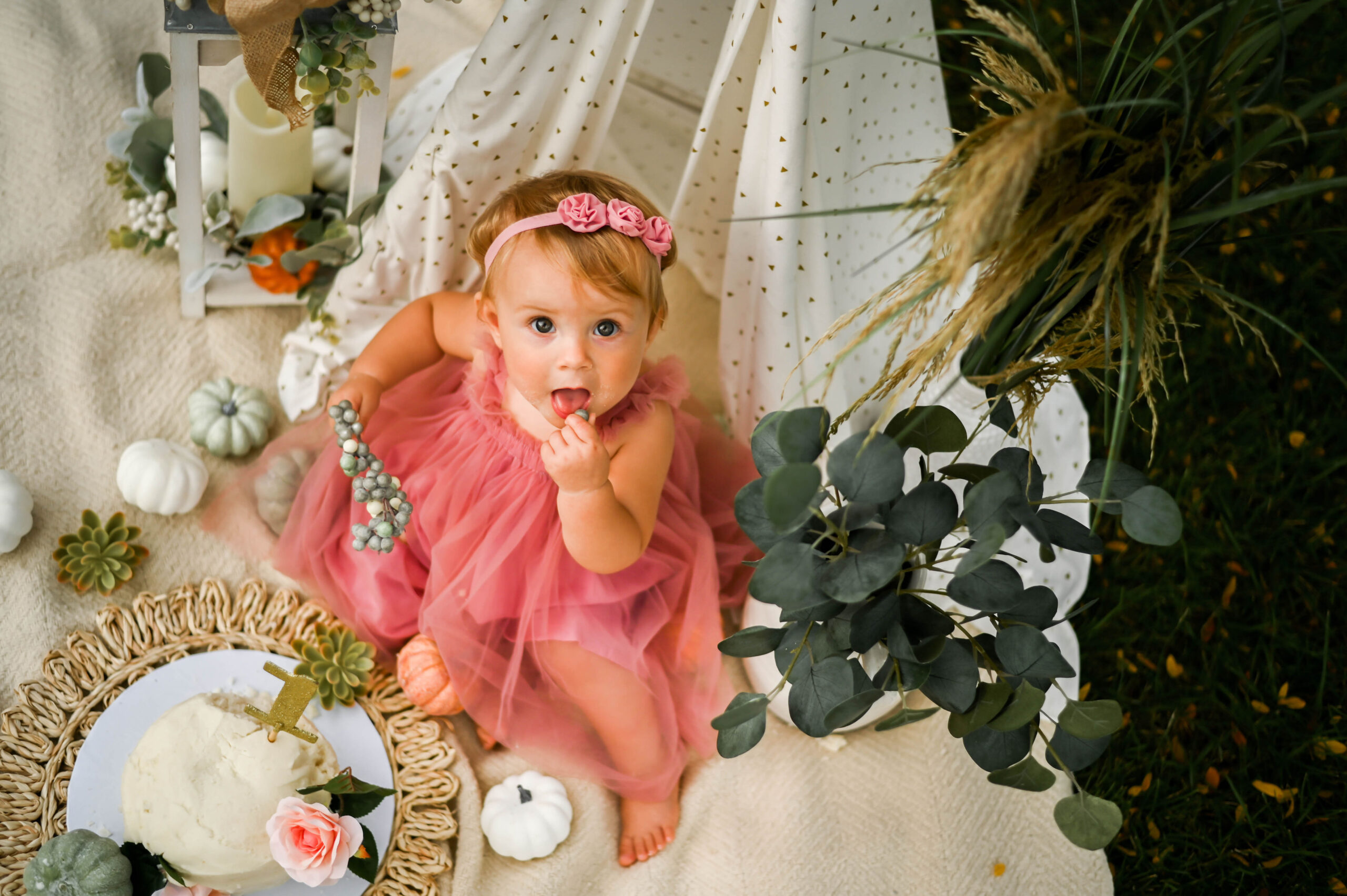 One year old girl in a pink tutu dress eating a birthday cake