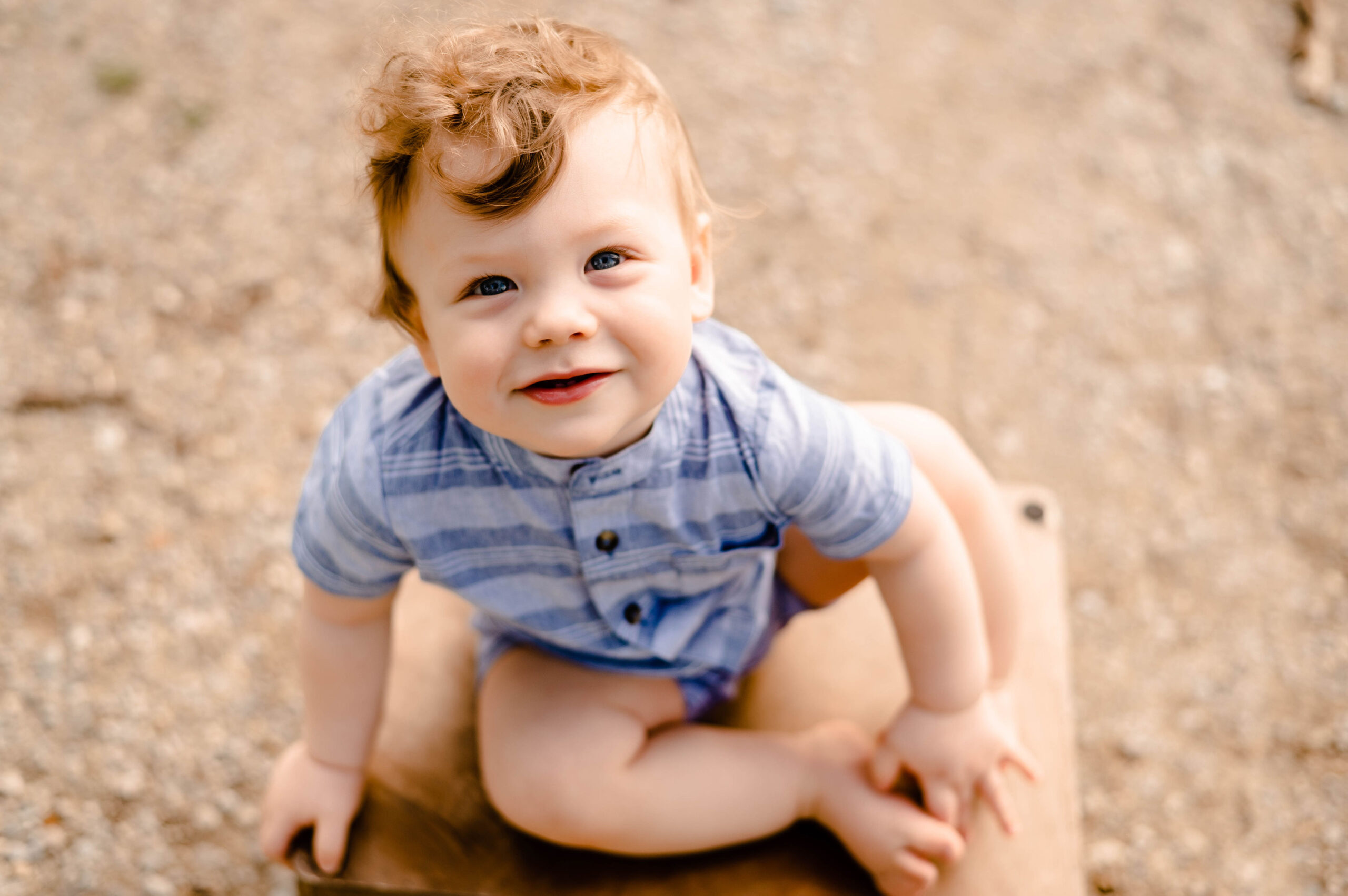 One year old boy sitting on a crate smiling at a park in Dayton, OH