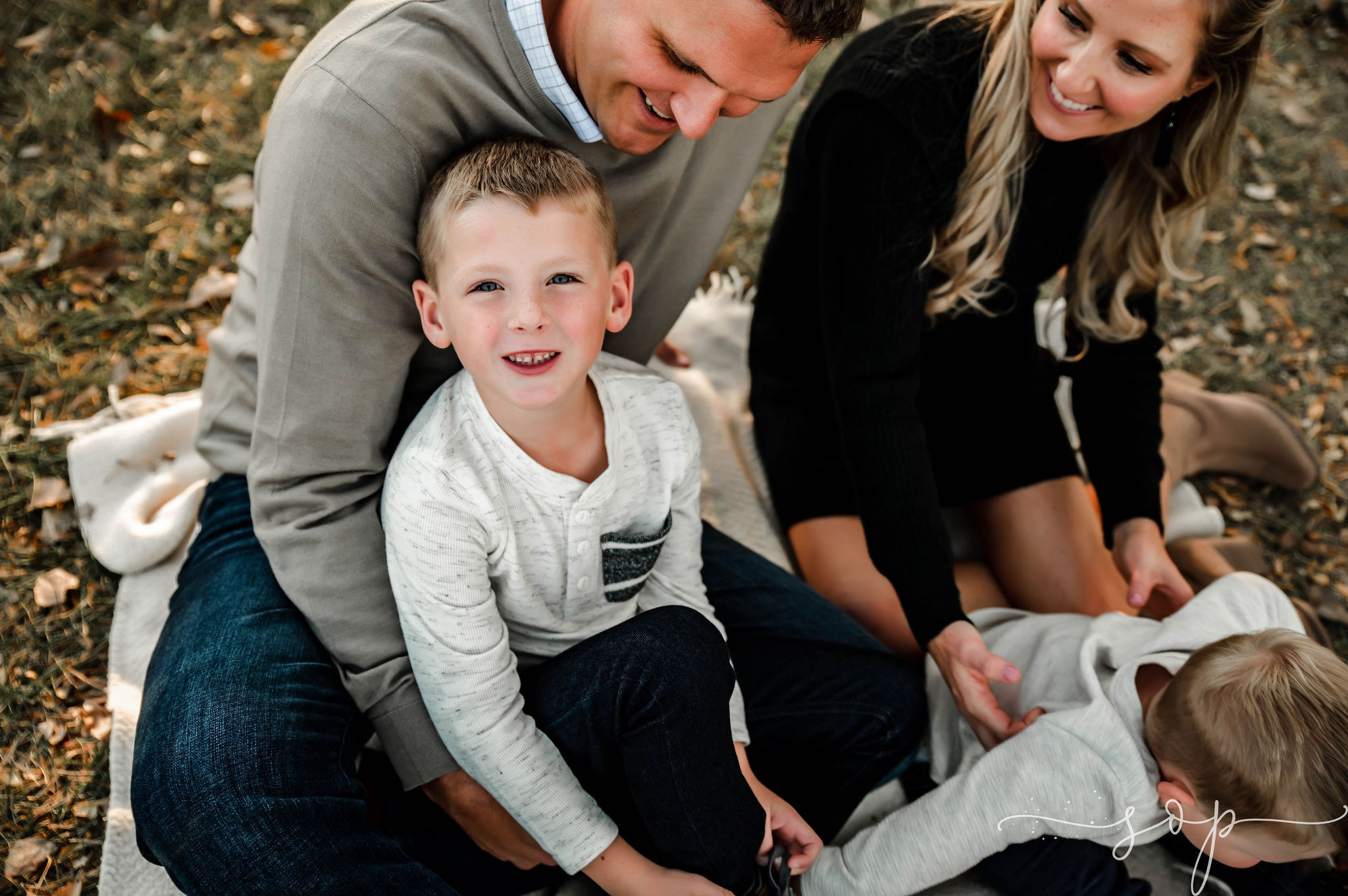 Family photos in the fall leaves. Close up of little boy looking and parents looking at him