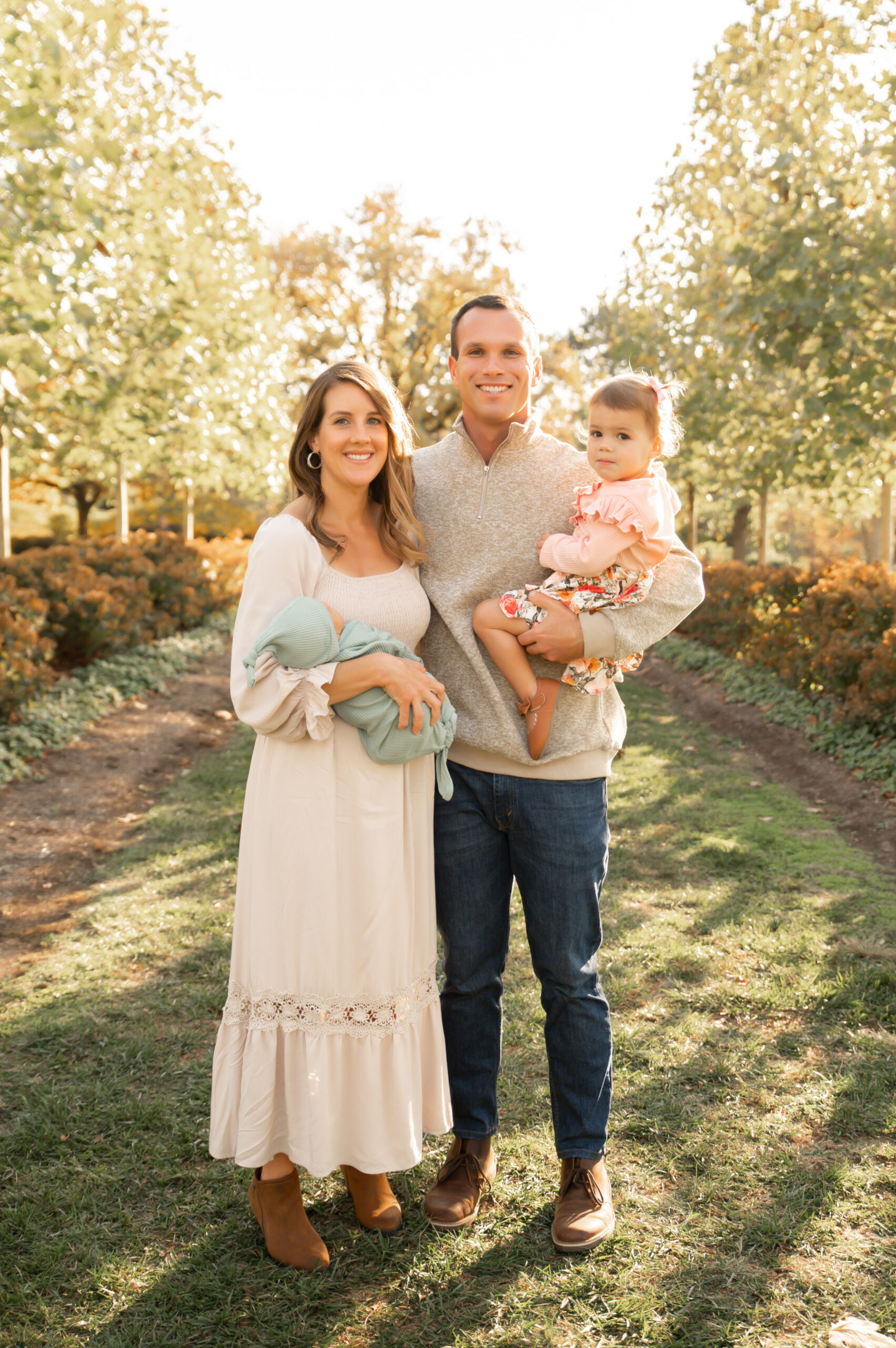 Newborn photos with family in row of beautiful trees. 